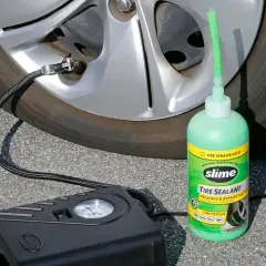 Un kit antipinchazos Slime, con su sellador verde y compresor negro, listo para reparar una rueda.