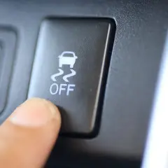 Dedo presionando el botón "OFF" del control de tracción, con el icono de un coche derrapando.