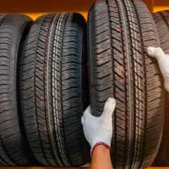 Manos enguantadas inspeccionan neumáticos nuevos, decidiendo si ponerlos delante o detrás.