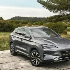 Un SUV gris moderno, uno de los coches híbridos autorrecargables, descansa sobre una plataforma de hormigón en un paisaje natural.