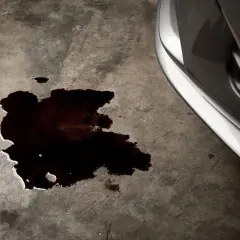 Mancha oscura de aceite en el suelo de hormigón, indicando una posible perdida de liquido en esa direccion.