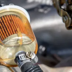 Filtro gasoil sucio con el elemento filtrante naranja visible y líquido amarillento.