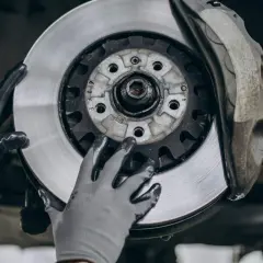 Manos enguantadas manipulan un disco de freno de coche, listo para ser reemplazado. A veces, solo se puede cambiar un disco de freno.