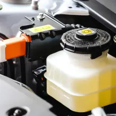 Depósito de líquido de frenos con líquido amarillo, listo para el cambio. Cables naranjas visibles.