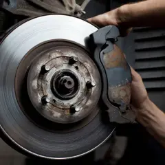 Mecánico revisa disco de freno desgastado. Averigua cuanto cuesta cambiar los discos de freno para tu seguridad.