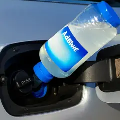 Botella de AdBlue vertiéndose en el depósito de un coche. ¿Qué pasa si me quedo sin AdBlue? El coche podría dejar de funcionar.