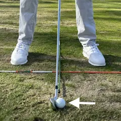 Jugador de golf en posición, con un palo y bola listos para el golpe. Los testigos averia Volkswagen Golf están en el campo, marcando la zona.