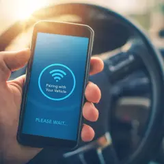 Mano sujetando un smartphone con pantalla que muestra "Pairing with Your Vehicle" y el icono de Bluetooth. Guía para saber como poner el bluetooth en el coche.