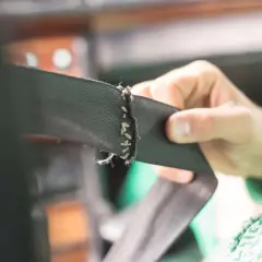 Mano intentando liberar un cinturón de seguridad atascado no sale, con costuras desgastadas.