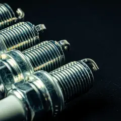 Cuatro bujías de encendido metálicas con rosca y aislante blanco, listas para dar vida a un motor. Los diesel llevan bujías, ¡y estas son las protagonistas!