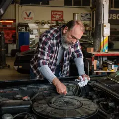 Mecánico revisa el motor de un coche clásico, buscando la causa por la que no salta el ventilador del coche.