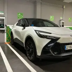 Coche híbrido blanco cargando en un parking. Las opiniones sobre este coche híbrido son muy positivas.