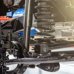 Detalle del sistema de suspensión de un coche, listo para cambiar amortiguadores delanteros. Se aprecian la rueda, el muelle y el amortiguador.