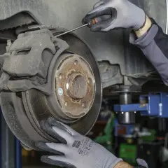 Mecánico revisa disco de freno y pinza, buscando la causa del molesto ruido al frenar.