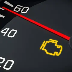 El tablero de un coche muestra el **luces cortas simbolo** del motor encendido, indicando un problema.