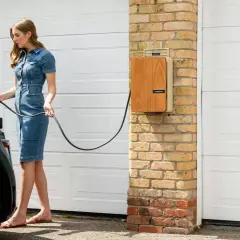 Mujer con vestido vaquero conecta cable a coche hibrido. Así se carga un coche hibrido en casa.