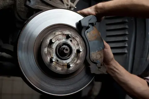 Mecánico revisa disco de freno desgastado. Averigua cuanto cuesta cambiar los discos de freno para tu seguridad.