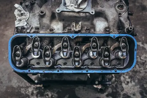 Detalle de balancines y resortes de un motor, con aceite visible, parte del sistema de lubricación.