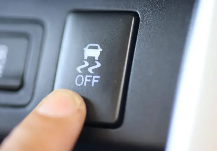 Dedo presionando el botón "OFF" del control de tracción, con el icono de un coche derrapando.