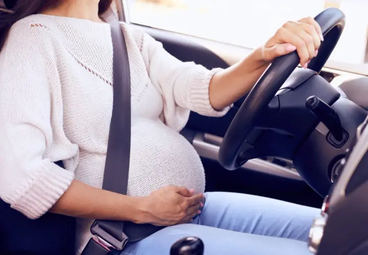 Mujer embarazada al volante con cinturón de seguridad. Un cinturón embarazada homologado DGT es esencial para su seguridad.