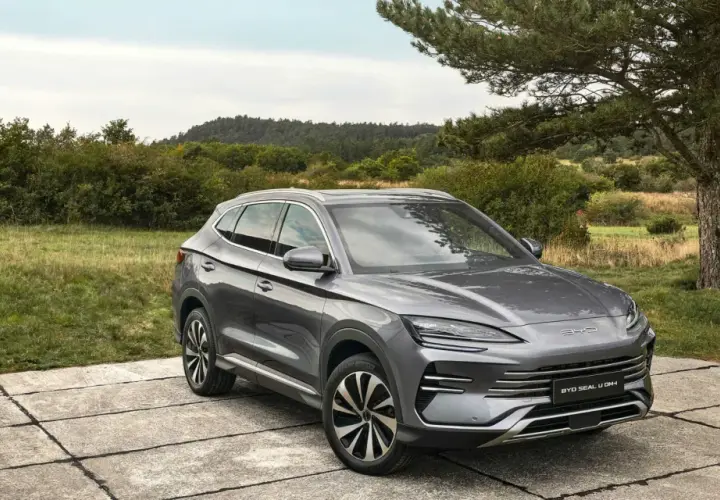 Un SUV gris moderno, uno de los coches híbridos autorrecargables, descansa sobre una plataforma de hormigón en un paisaje natural.