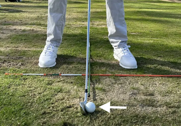 Jugador de golf en posición, con un palo y bola listos para el golpe. Los testigos averia Volkswagen Golf están en el campo, marcando la zona.