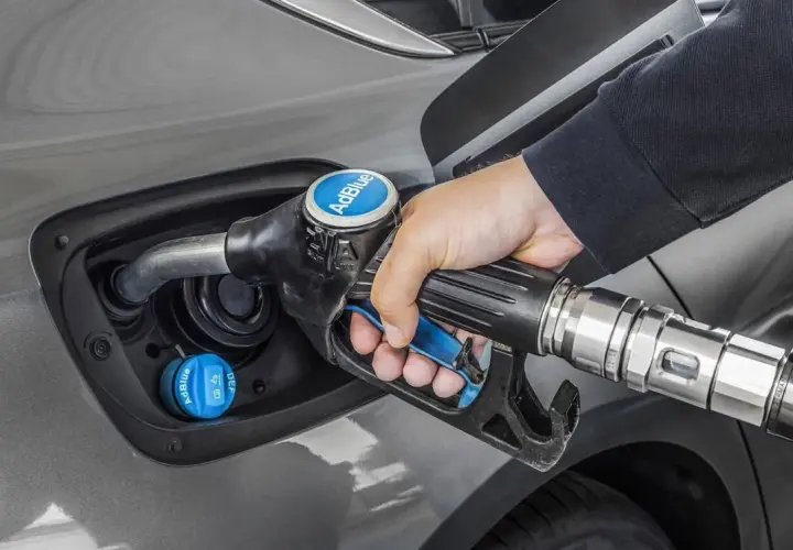 Persona rellena el depósito de AdBlue de un coche. Saber cuanto AdBlue consume un coche es clave para planificar repostajes.