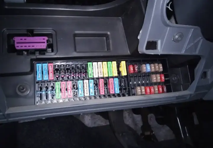 Panel de fusibles de un Seat Ibiza 6J con varios fusibles de colores y un conector púrpura.