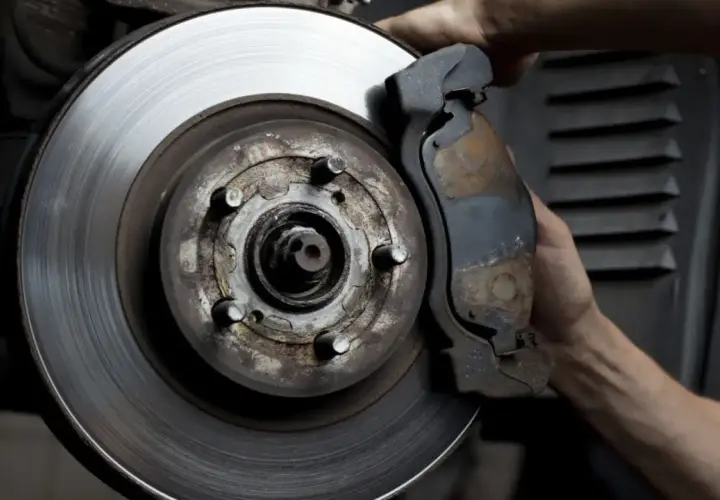 Mano ajustando la pinza de freno a un disco con rebaba.