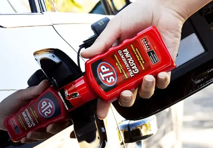 Persona añadiendo aditivo STP a un coche de gasolina para su mantenimiento.