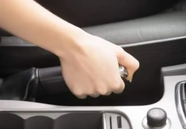 Mano tensando el freno de mano de un Volvo XC90.