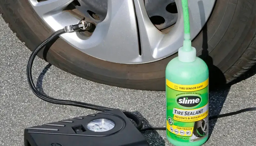 Un kit antipinchazos Slime, con su sellador verde y compresor negro, listo para reparar una rueda.
