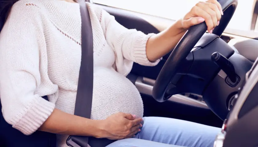 Mujer embarazada al volante con cinturón de seguridad. Un cinturón embarazada homologado DGT es esencial para su seguridad.