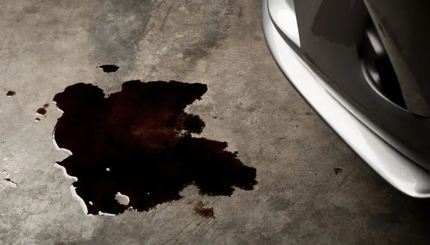 Mancha oscura de aceite en el suelo de hormigón, indicando una posible perdida de liquido en esa direccion.