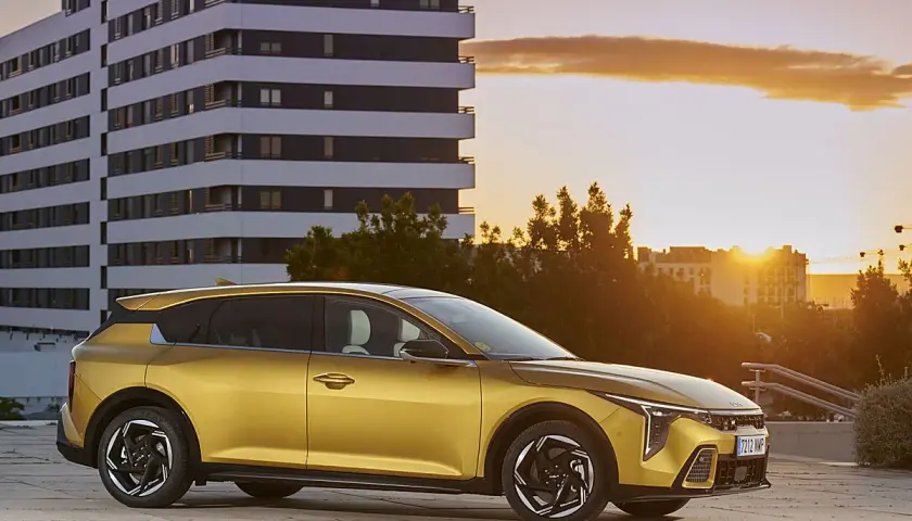 Coche dorado moderno aparcado frente a un edificio al atardecer. ¿Buscas cómo bajar el CO2 de un coche de gasolina?