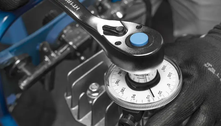 Mano con guante ajusta una llave dinamométrica con dial, mostrando cómo funciona una llave dinamométrica para aplicar el par correcto.