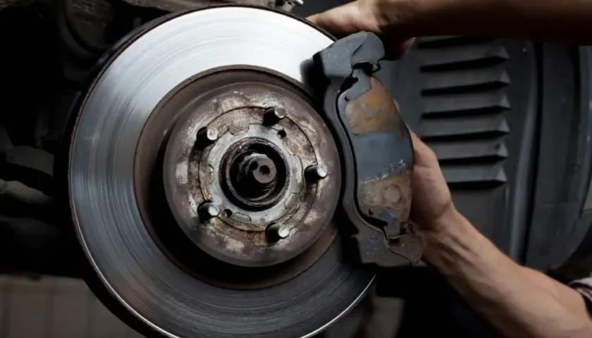Mecánico revisa disco de freno desgastado. Averigua cuanto cuesta cambiar los discos de freno para tu seguridad.