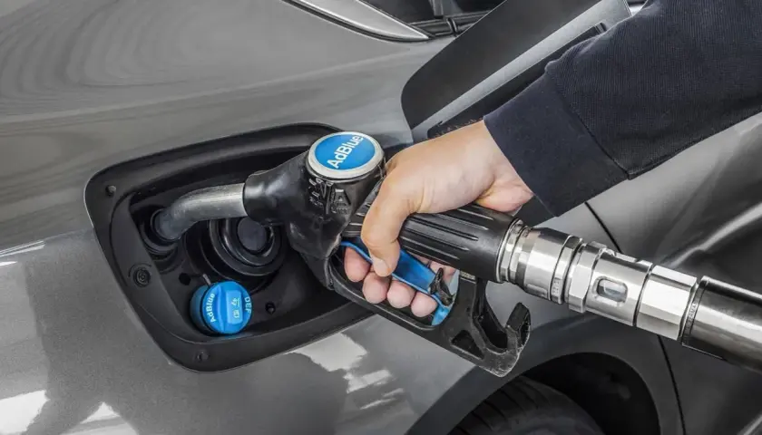 Persona rellena el depósito de AdBlue de un coche. Saber cuanto AdBlue consume un coche es clave para planificar repostajes.