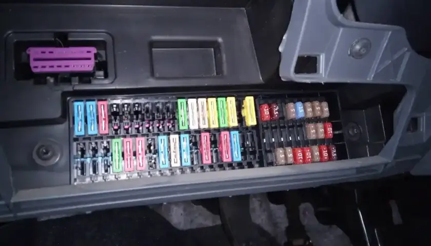 Panel de fusibles de un Seat Ibiza 6J con varios fusibles de colores y un conector púrpura.