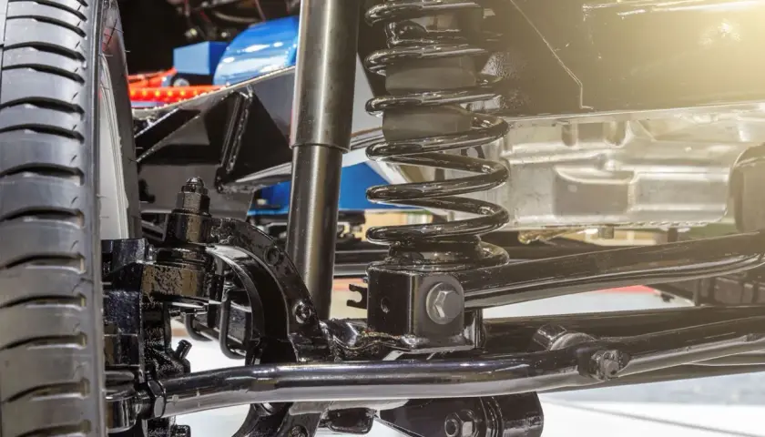 Detalle del sistema de suspensión de un coche, listo para cambiar amortiguadores delanteros. Se aprecian la rueda, el muelle y el amortiguador.