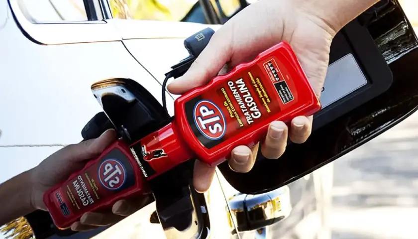 Persona añadiendo aditivo STP a un coche de gasolina para su mantenimiento.