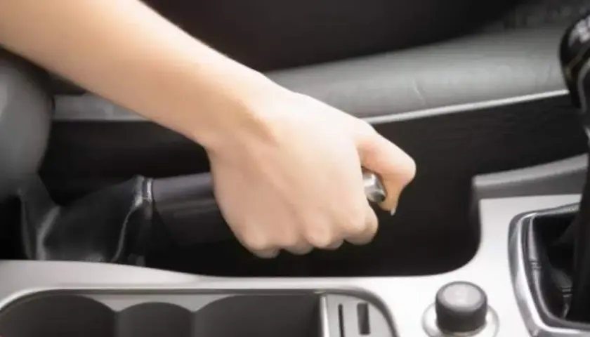 Mano tensando el freno de mano de un Volvo XC90.