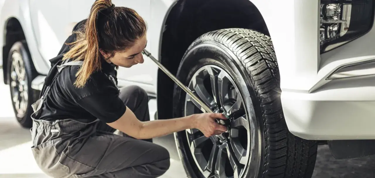 Mecánica trabajando en el cambio de ruedas de un coche.