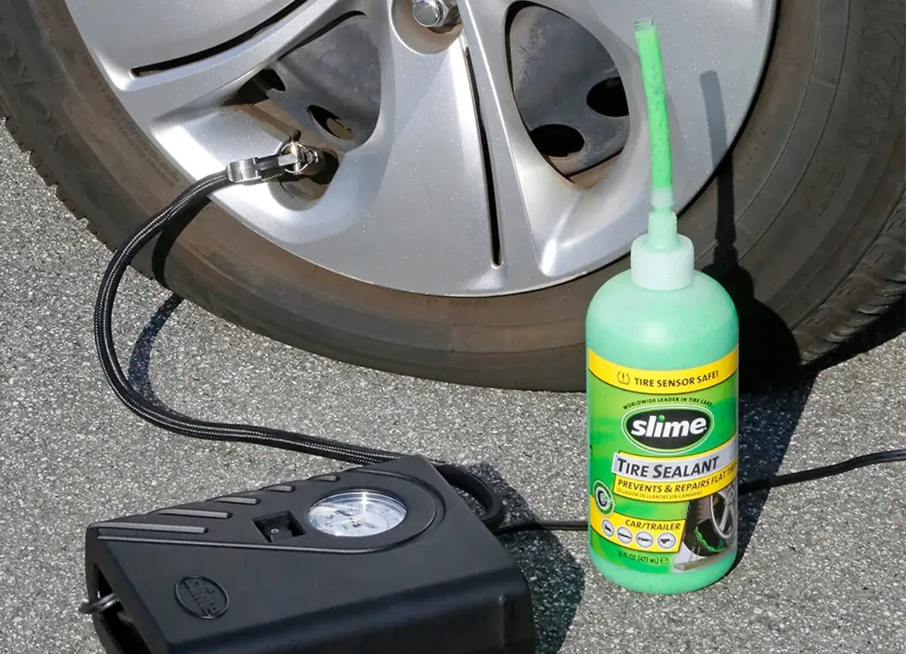 Un kit antipinchazos Slime, con su sellador verde y compresor negro, listo para reparar una rueda.