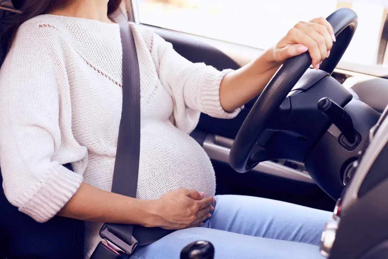 Mujer embarazada al volante con cinturón de seguridad. Un cinturón embarazada homologado DGT es esencial para su seguridad.