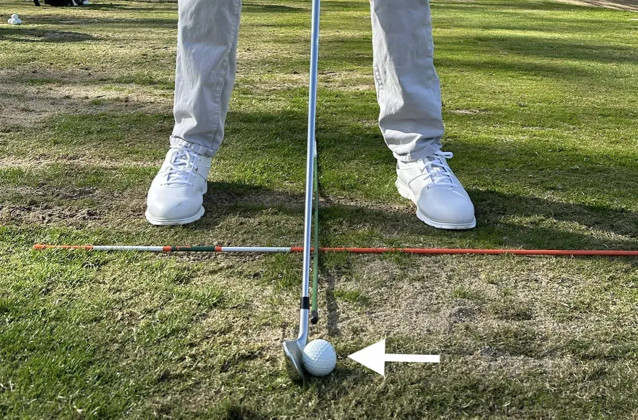 Jugador de golf en posición, con un palo y bola listos para el golpe. Los testigos averia Volkswagen Golf están en el campo, marcando la zona.