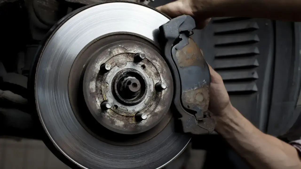 Mano ajustando la pinza de freno a un disco con rebaba.