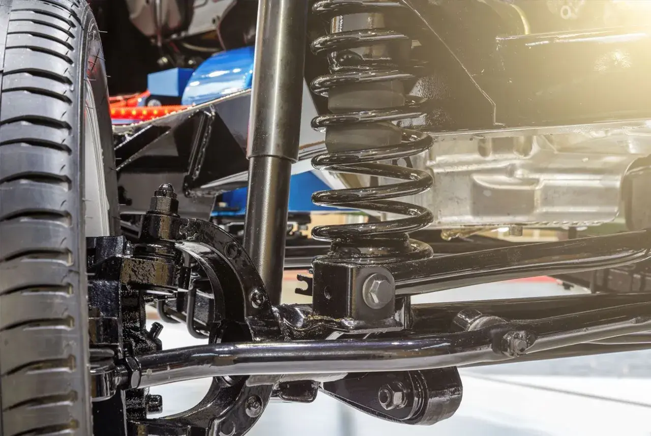 Detalle del sistema de suspensión de un coche, listo para cambiar amortiguadores delanteros. Se aprecian la rueda, el muelle y el amortiguador.