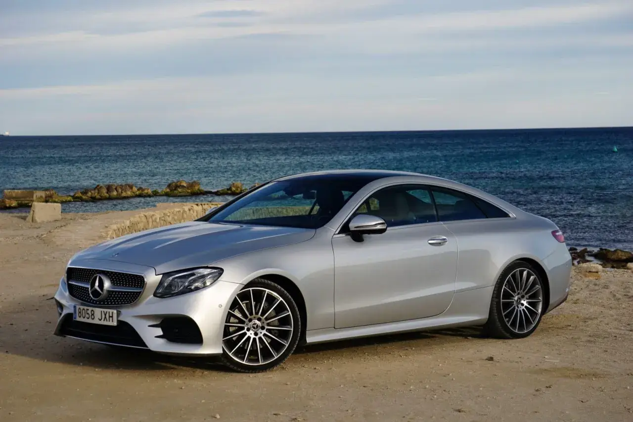 Mercedes-Benz E 220d Coupé plateado, 194 CV. Opiniones sobre su motor y diseño junto al mar.