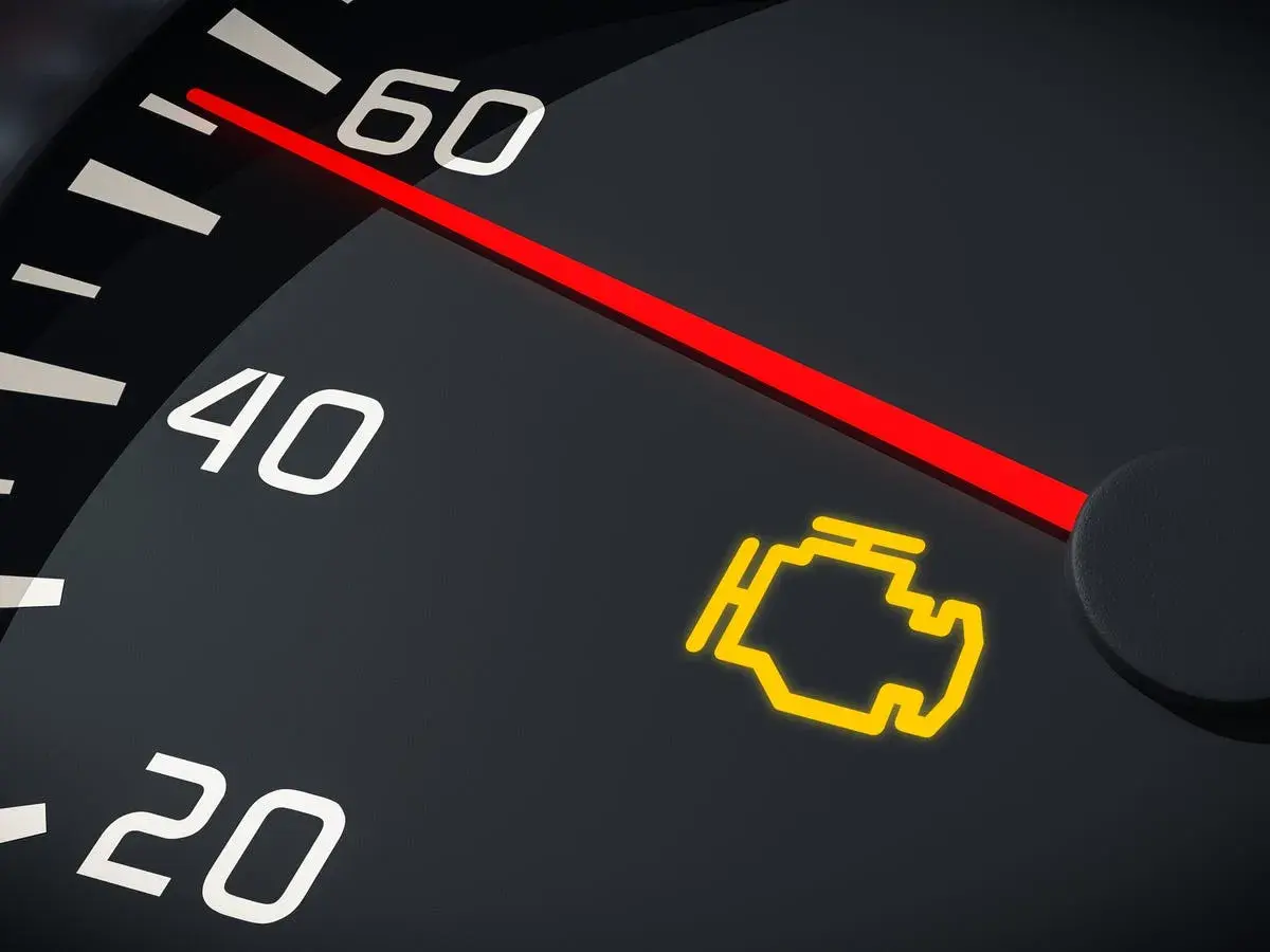 El tablero de un coche muestra el **luces cortas simbolo** del motor encendido, indicando un problema.